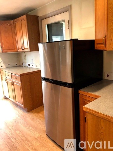 A kitchen with a stainless steel refrigerator and wooden cabinets.