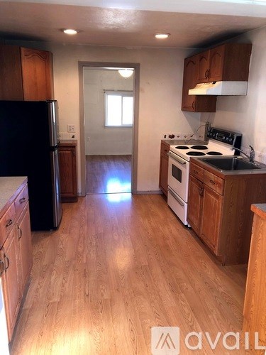 A kitchen with wooden floors and black appliances.