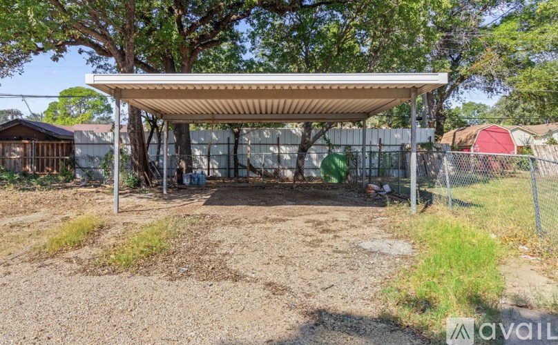 A covered outdoor area with a gravel ground and a fence.