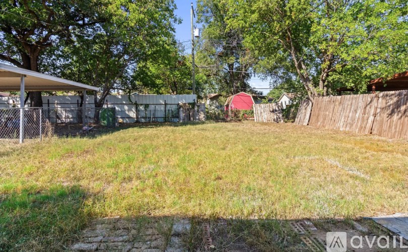 A grassy field with a fence and trees in the background.
