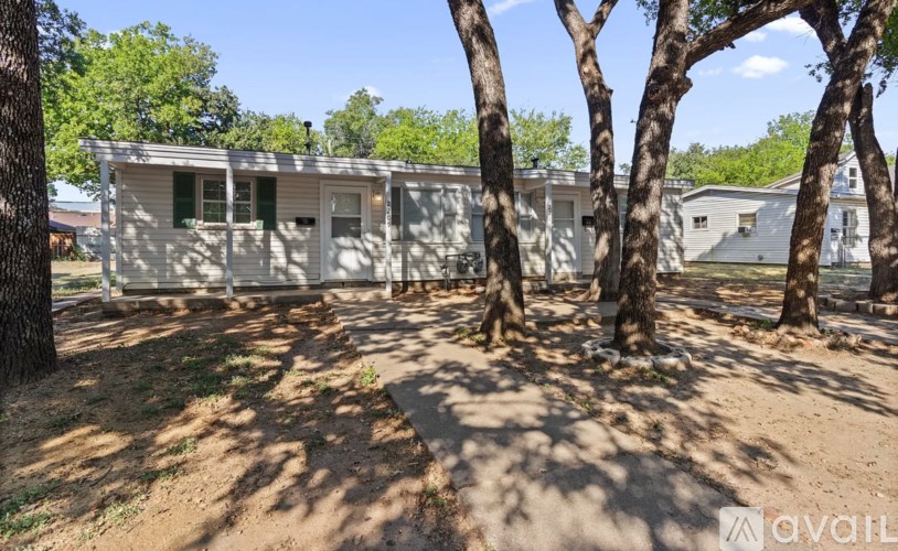 A mobile home sits in a grassy area with trees in the foreground.