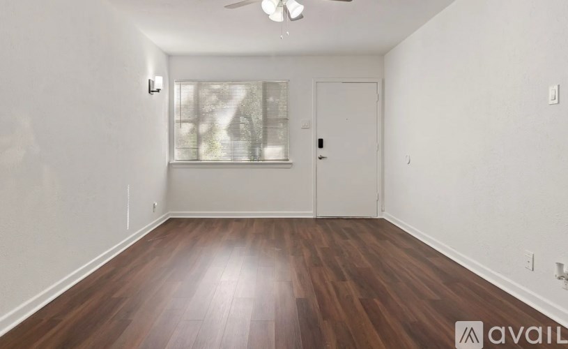 A room with wooden flooring and a window with blinds.