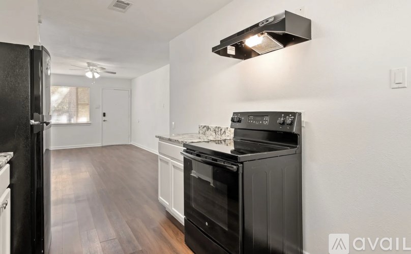 A modern kitchen with black appliances and wooden floors.