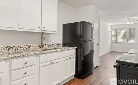 A kitchen with white cabinets and a black refrigerator.