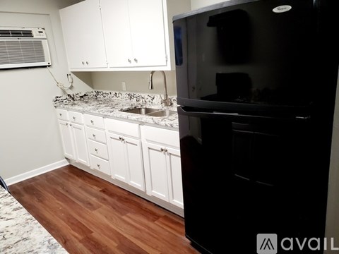 A kitchen with white cabinets and a black refrigerator.