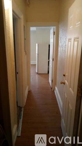 A hallway with a wooden floor and white walls.