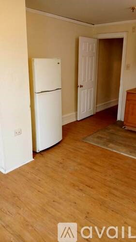 A kitchen with a white fridge and wooden floors.