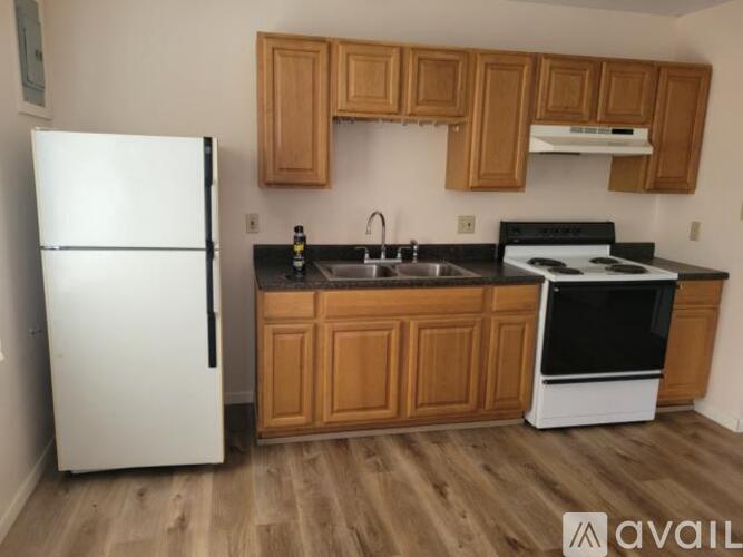 A kitchen with a white fridge, wooden cabinets, and a black stove top oven.