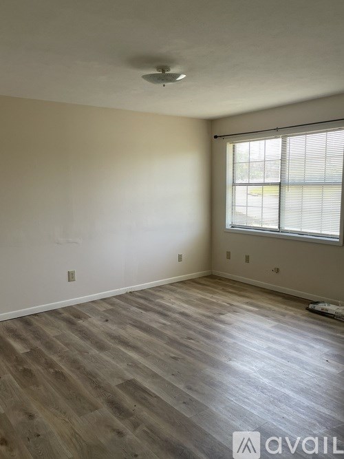 A room with wooden flooring and a window with blinds.