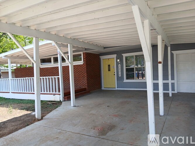A covered porch area with a yellow door and white pillars.