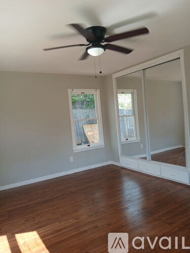 A room with a ceiling fan and wooden flooring.