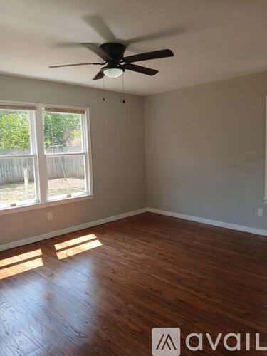 A room with a ceiling fan and wooden flooring.