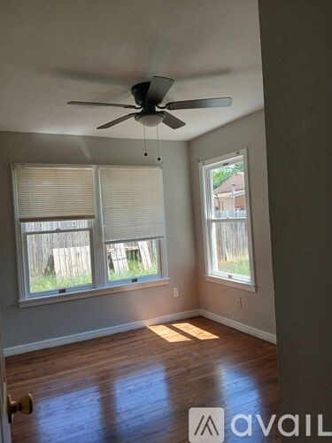 A room with a ceiling fan and two windows.