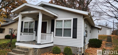A small house with a porch and a front yard.