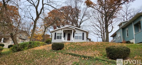 A house with a hill in front of it and trees in the background.