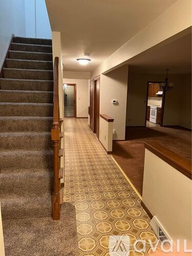 A hallway with a staircase on the left and a door on the right.