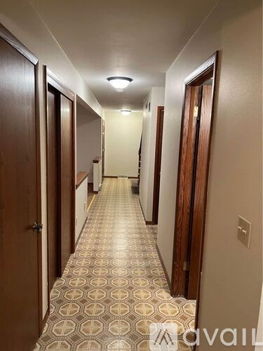 A long hallway with doors on both sides and a tiled floor.