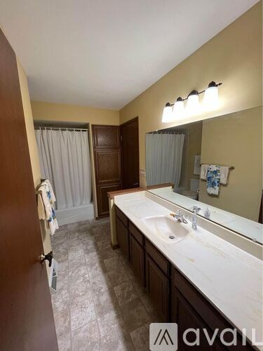 A bathroom with a sink, mirror, and a towel hanging on the door.