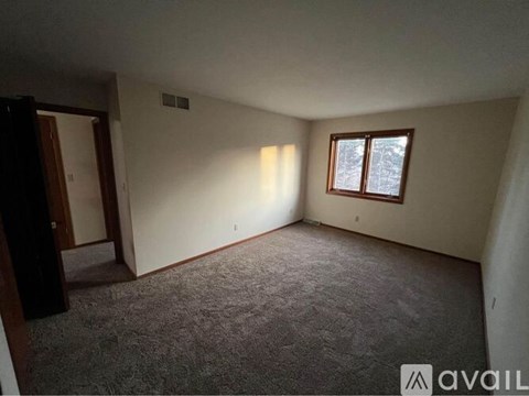 A room with a carpeted floor and a window with a white frame.