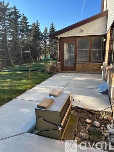 A beehive is placed on a concrete slab outside a house.