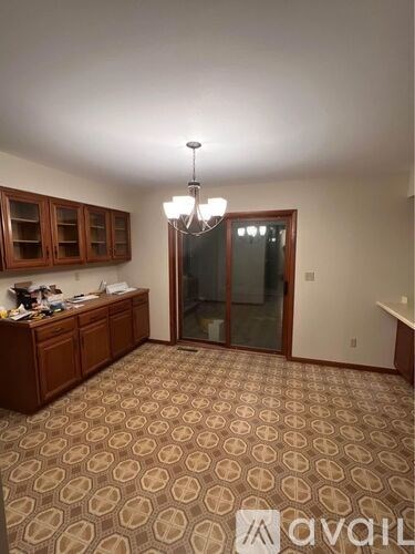 A room with a carpeted floor and a chandelier hanging from the ceiling.