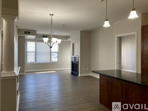 A spacious living room with a dark wood floor and a black countertop.