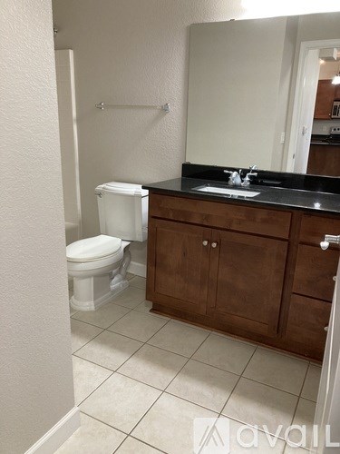 A bathroom with a toilet, sink, and cabinets.