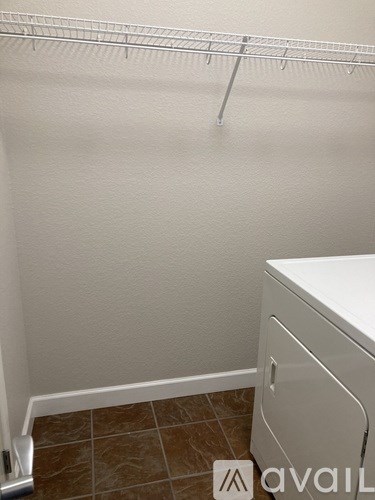 A white dryer is sitting next to a white wall.