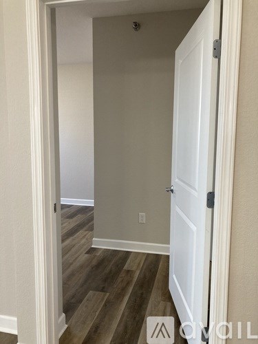 A hallway with a white door and wood flooring.