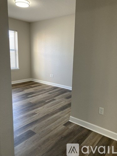 A room with wooden flooring and a window with blinds.