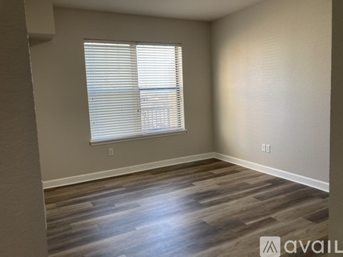 A room with wooden flooring and a window with blinds.