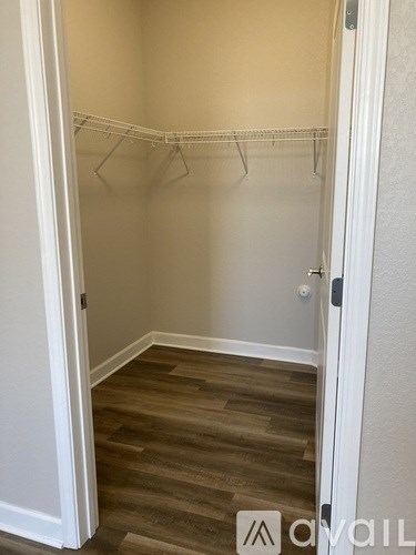 A small, empty closet with a wooden floor and white walls.