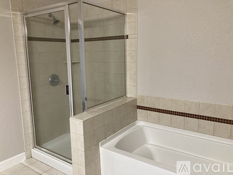 A white bathtub sits next to a glass shower door in a bathroom.