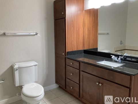 A bathroom with a toilet, sink, and wooden cabinet.