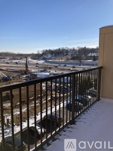 A view from a balcony overlooking a parking lot and a field.