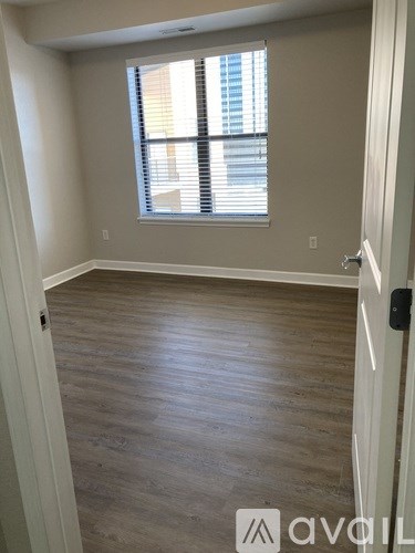 A room with wooden flooring and a window with blinds.