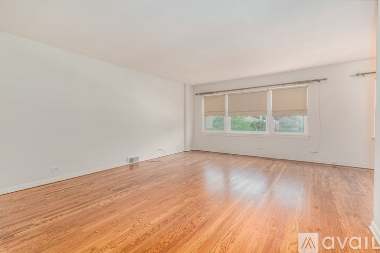 A room with wooden flooring and a window with blinds.