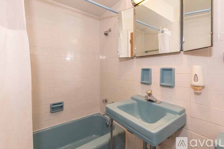 A bathroom with a blue sink and a white towel hanging on the tub.