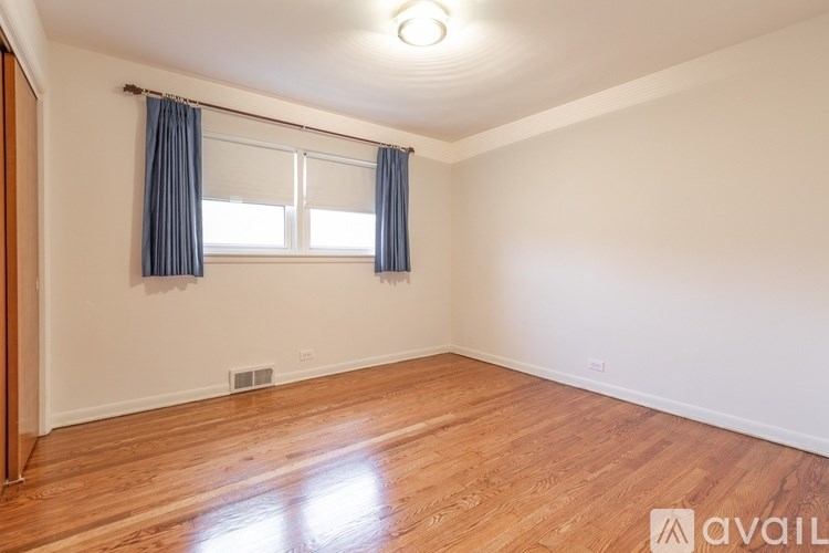 A room with wooden flooring and a window with blue curtains.