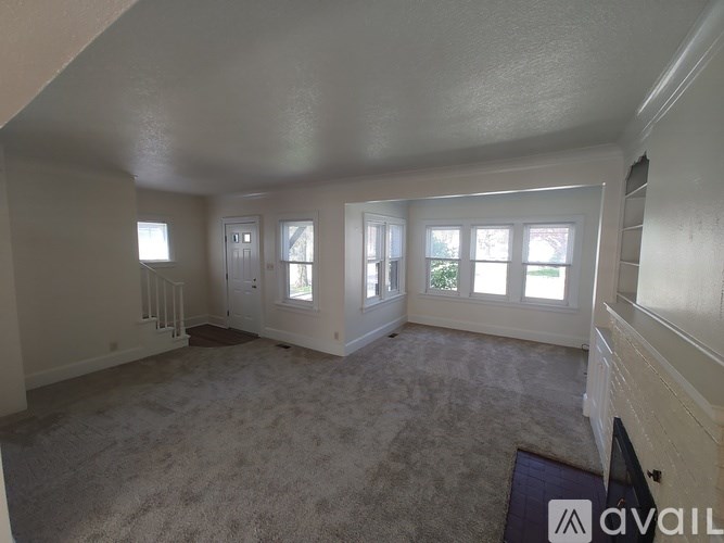 A room with carpeted floor and a window with blinds.