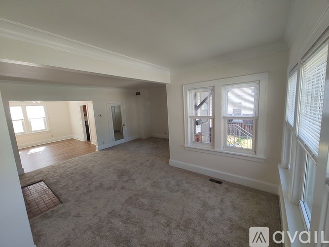 A spacious room with a carpeted floor and two windows.