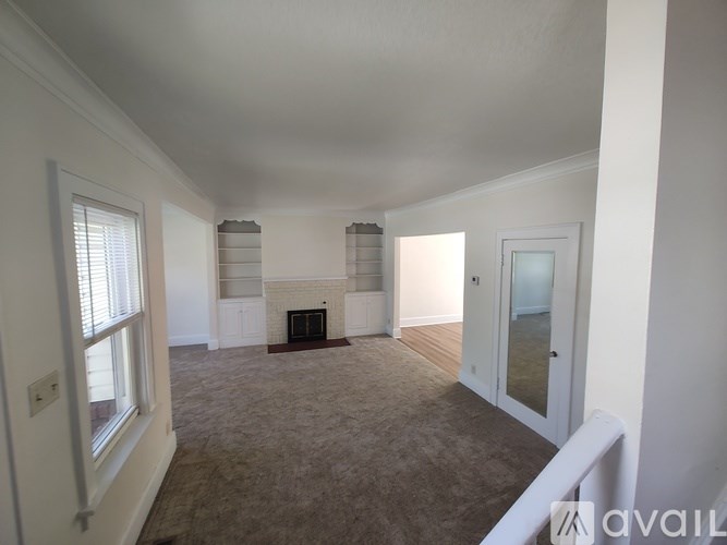 A spacious living room with a fireplace and a carpeted floor.