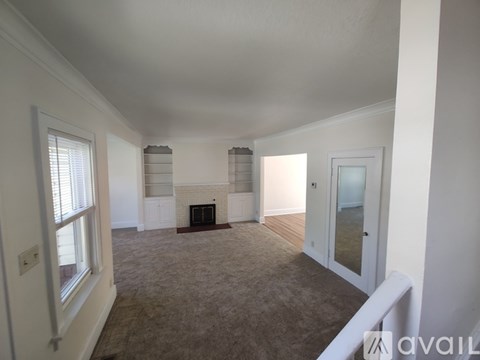 A spacious living room with a fireplace and a carpeted floor.