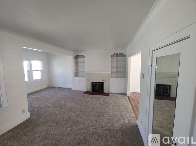 A spacious living room with a fireplace and a carpeted floor.