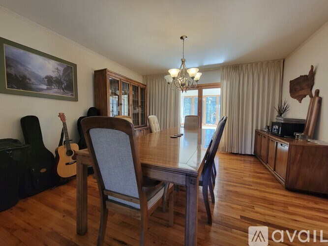 A dining room with a wooden table and chairs, a guitar, and a painting on the wall.