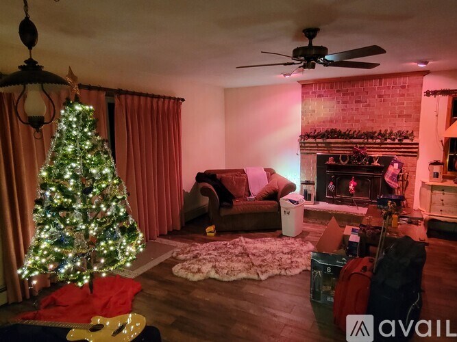 A Christmas tree stands in a living room with a fireplace and a couch.