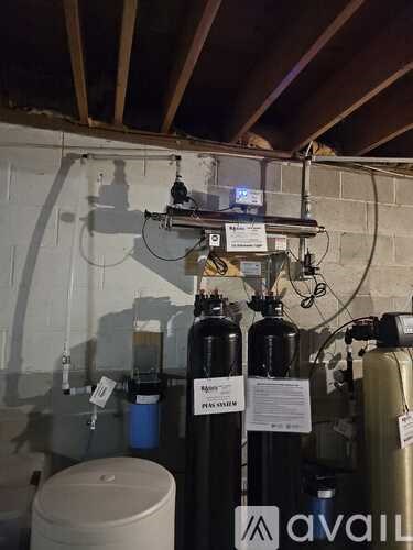 A room with a white ceiling and a wall with pipes and a tank.