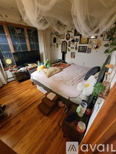 A room with a bed, a chair, and a table with a vase of flowers on it.