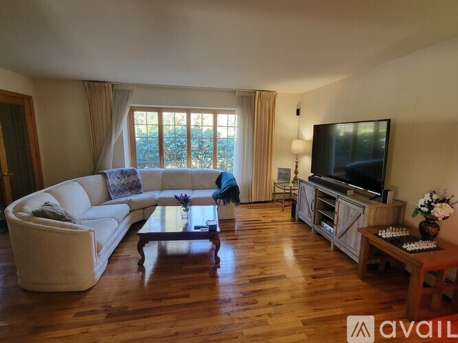 A living room with a white couch, a wooden coffee table, and a television.