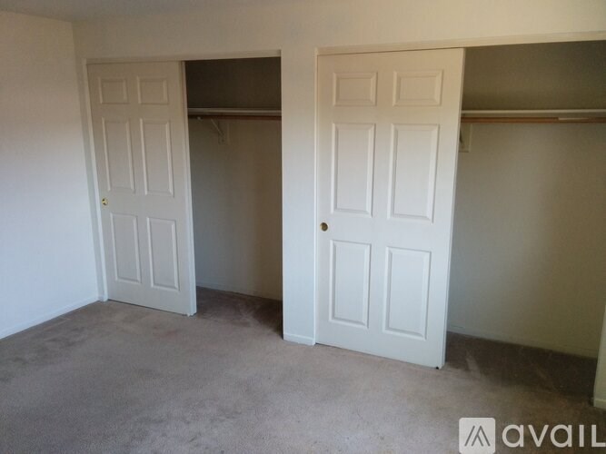 Two white doors in a room with carpeted floor.